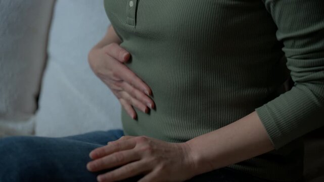 Close-up of a person holding their stomach, showing signs of abdominal pain or discomfort. health issues, digestive problems, and physical distress in everyday life.