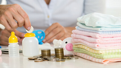 Parenting Costs Concept. Budgeting with coins and baby items, including bottles and diapers, evokes sense of preparation and care