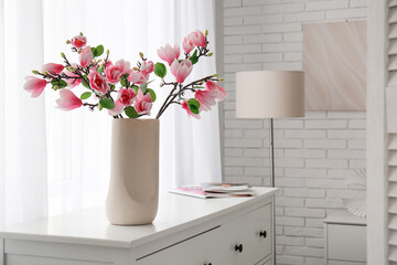 Vase with beautiful magnolia flowers on chest of drawers in stylish bedroom © Pixel-Shot