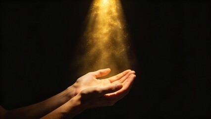 Fototapeta premium Cupped human hands receiving a glowing golden beam of light on a black background symbolizing spirituality and magic with copy space
