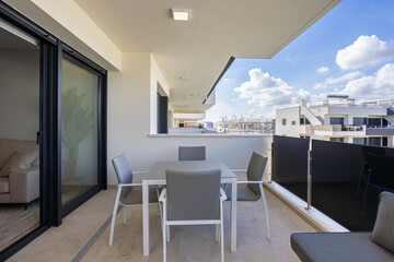 Naklejka premium Covered modern balcony with dining table and scenic residential building view