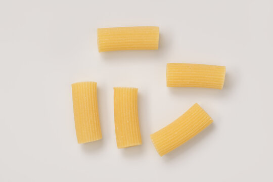 Italian dry rigatoni pasta over white background with shadow top view