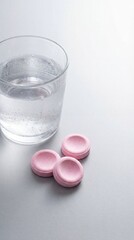 Antacid tablets near water glass on a gray background  