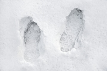 Obraz premium Pair of boots or shoes track in the snow. Pair of footprints in the snow. Texture of snow surface. Top view. Close-up. 