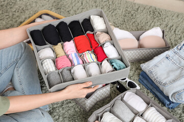 Beautiful young woman with clean clothes in organizers at wardrobe, closeup