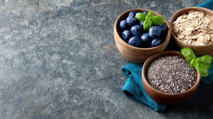 Bowls of fruits, seeds, and oats on a stone surface with a blue cloth during daylight