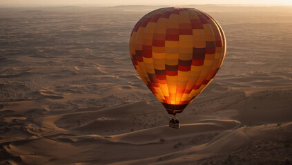 Obraz premium Vibrant orange hot air balloon glowing above desert dunes at sunrise, serene adventurous mood