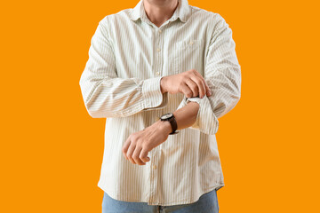 Mature man rolling up his sleeve on yellow background, closeup