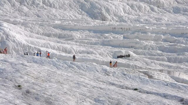 Kiteboarding and kitesurfing as a kiter is pulled across sea water by a power kite. Kiteboarders and kitesurfers ride wind power near the beach for extreme sea sport.