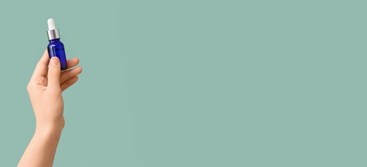 Hand holding bottle of cosmetic serum on color background with space for text