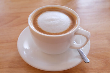 Cappuccino coffee in white cup on wooden table, stock photo