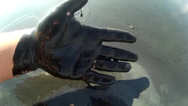 A close-up of a male hand gently moving in healing volcanic mud at a mineral lake under bright sunlight. This serene scene highlights alternative medicine, mineral therapy, and natural wellness 