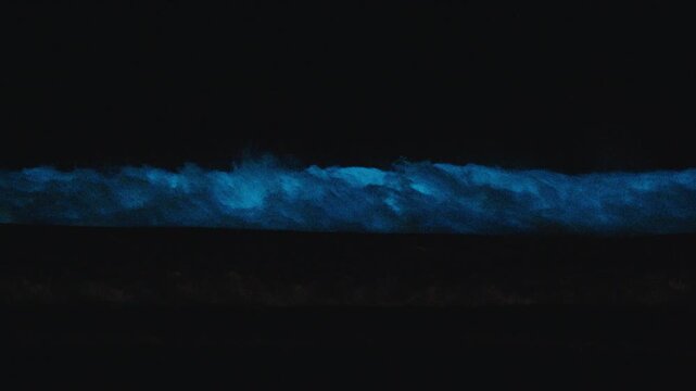 Bioluminescence of the ocean wave. Pack of several footages of the night sea with breaking waves shining strong blue light caused by bioluminescence. High level of noise