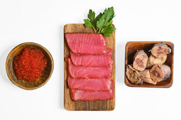 Freshly sliced fish with fish roe and preserved fish on a wooden platter in a clean kitchen setting