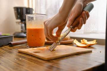 Grating fresh ginger on a wooden cutting board in a kitchen