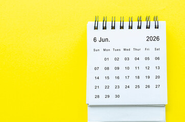 Top view of June 2026 table calendar with space for text on yellow background.