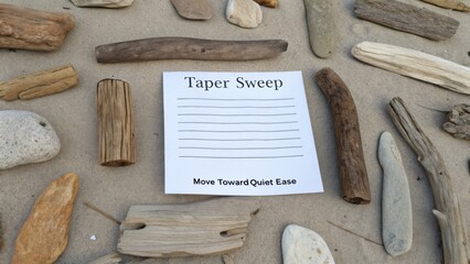 Taper Sweep on Sand Surrounded by Various Natural Driftwood, Eucalyptus Wood and Pebbles for Relaxation and Mindfulness Journaling