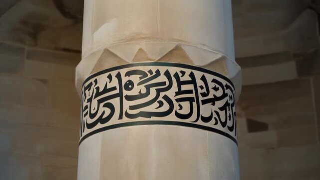 Calligraphy on a Minaret Shaft. Islamic Culture &ndash; Building and Architecture. Smooth minaret shaft where a wide band of striking black Thuluth script calligraphy wraps around the stone structure.
