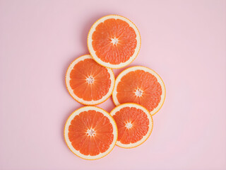 A close up of a pink background with a group of grapefruit slices on it