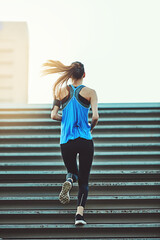 Obraz premium Back, running and woman on stairs for fitness, training and exercise for wellness. Outdoor, female person and runner for workout, muscle development and endurance with health challenge in New York