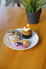 a cupcake on a white plate on a wooden table, breakfast menu in the morning, with natural lighting in the morning