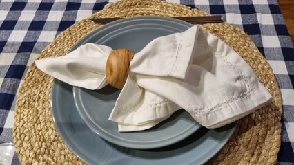 table setting, classic tablecloth with a blue and white check, wicker round stand and gray plates....