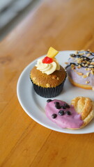 a cupcake on a white plate on a wooden table, breakfast menu in the morning, with natural lighting in the morning