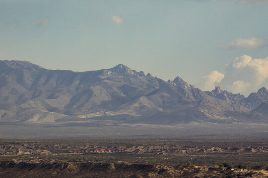 Distant train dwarfed by looming mountainous background