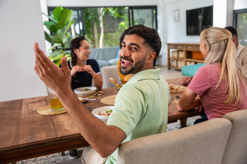 Diverse friends eating noodle bowls with chopsticks on wooden dining table in dining area © wavebreak3