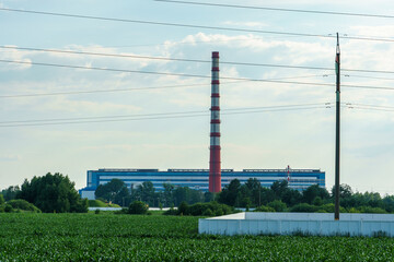 Obraz premium The tall chimney of a modern power plant against the sky. Electricity generation, an industrial development concept.