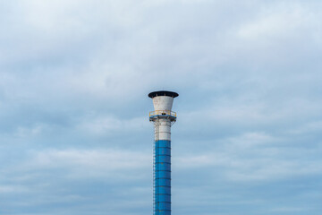 A smokeless factory chimney against the sky and clouds. The concept of industrial development.