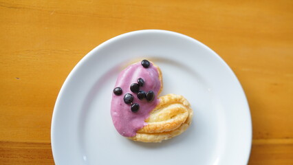 a cupcake on a white plate on a wooden table, breakfast menu in the morning, with natural lighting in the morning
