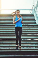 Obraz premium Running, music and stairs with woman in city for health, workout playlist and cardio challenge. Wellness, exercise podcast and low angle with person and earphones for runner training and endurance