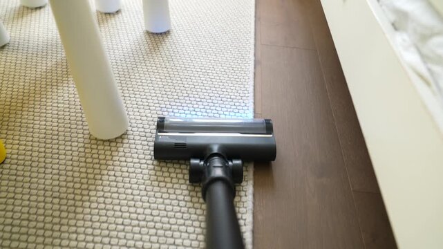 Top view of a vacuum cleaner, vacuuming a beige carpet on a parquet floor, video of house cleaning.