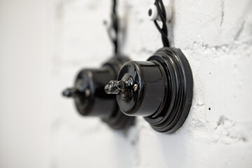 Vintage ceramic black light switch on the white brick wall. Switches in retro. 