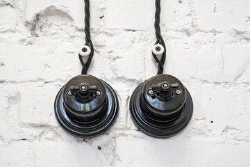 Vintage ceramic black light switch on the white brick wall. 