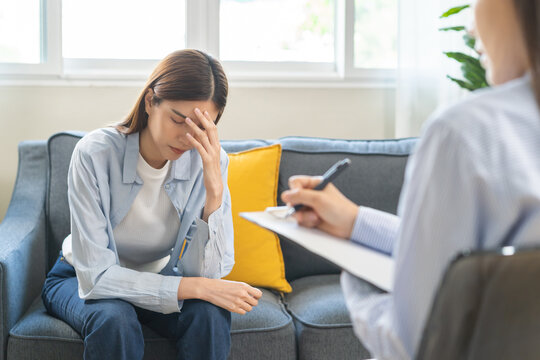 Psychology, depression. Suffer asian young woman consultation with psychologist while patient counseling mental therapy, doctor hand taking notes at clinic. Psychologist with sick mental health person