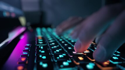 Close-up view of hands typing on a modern, vibrantly illuminated computer keyboard, highlighting the immersive interaction with advanced digital technology in a dark environment - Powered by Adobe