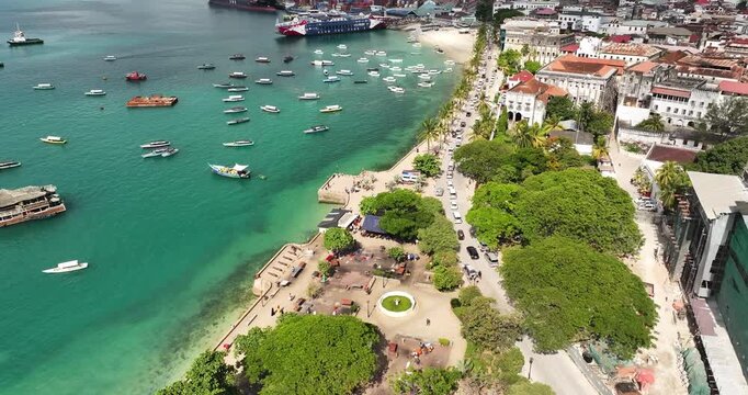 Cinematic aerial drone flight above Forodhani Gardens in Stone Town, Zanzibar. Oceanfront park, historic architecture,coastal atmosphere create a vibrant scene ideal for travel and tourism project.
