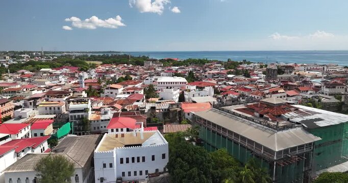 Cinematic aerial drone flight over the House of Wonders and historic rooftops of Stone Town, Zanzibar. Swahili architecture, coastal atmosphere, and timeless city textures create a stunning travel sce