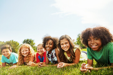 Portrait, friends and children on lawn with smile, bonding and diversity together on vacation. Happy kids, boys and girls on grass outdoor to relax in nature with group for hang out with space © BuyoutReese05/peopleimages.com