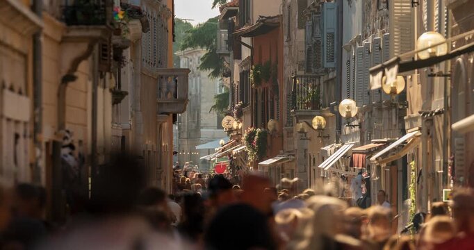 Porec, Croatia - August 13, 2025: Timelapse, zoom in transition. Crowded narrow cobbled street in Porec old town filled with tourists during a sunny summer evening in Croatia