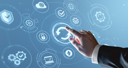 Business hand touching update icon on futuristic digital interface with cloud, gear, and security symbols over blue background.