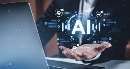Businessman holding AI hologram with chatbot icons and digital communication symbols in futuristic workspace background to illustrate AI technology concept.