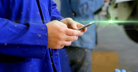 Mature worker tapping smartphone in industrial workshop, displaying animated data graphs - Powered by Adobe