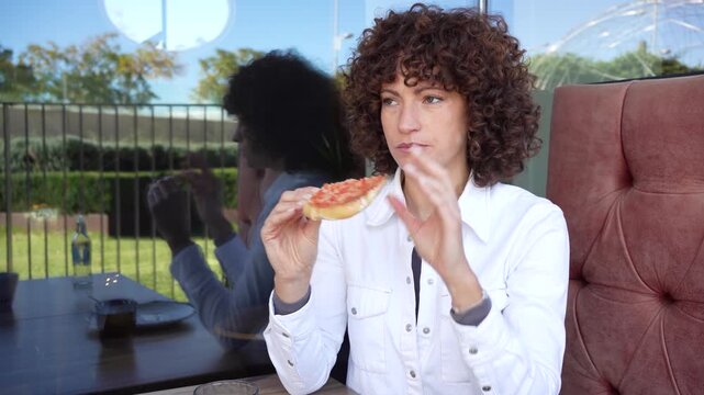 A Thoughtful Woman Sitting in a Cozy Cafe, Sporting Curly Hair and Gazing at a Reflective Window