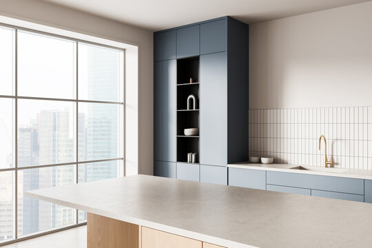 Modern minimalist kitchen interior with blue cabinets, tiled backsplash, and large window overlooking cityscape in daylight concept background design. 3D Rendering