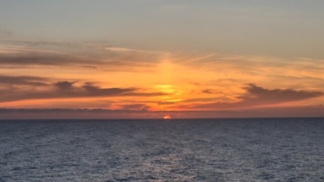 Sunset ocean seascape amazing vertical shot of fiery orange and yellow clouds over the dark blue horizon during twilight