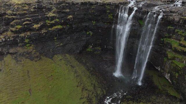 Stunning aerial shot of the impressive Fossa waterfall cascading down a rocky cliff in Streymoy