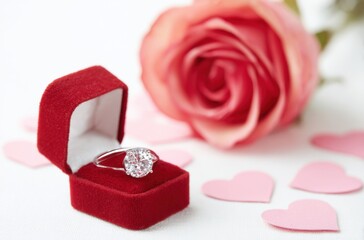 A red velvet box with a diamond ring inside